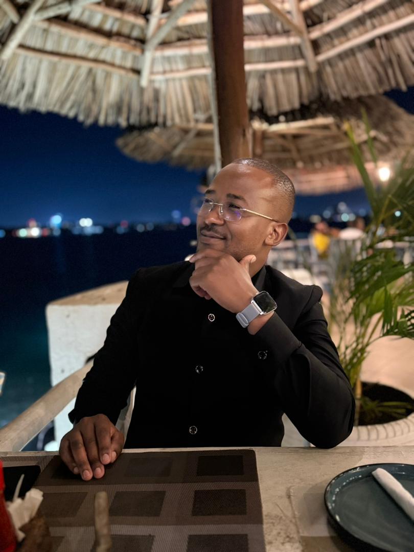 Portrait of Davis Amani seated at an evening venue.