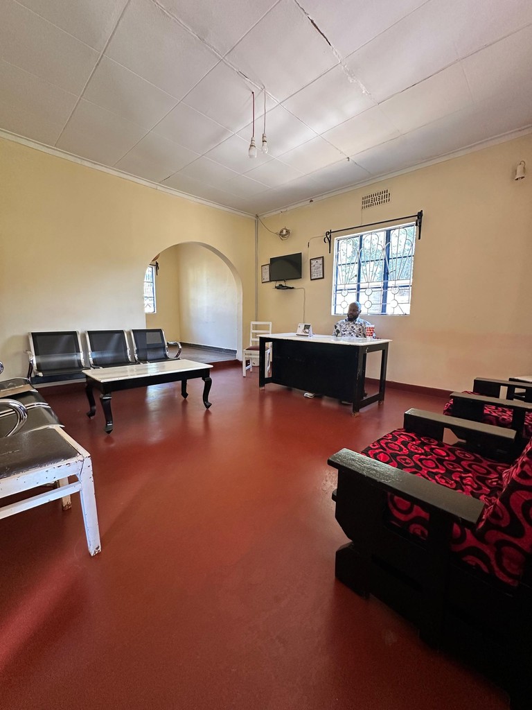 An indoor room with a table-tennis table, seating, a desk and a window.