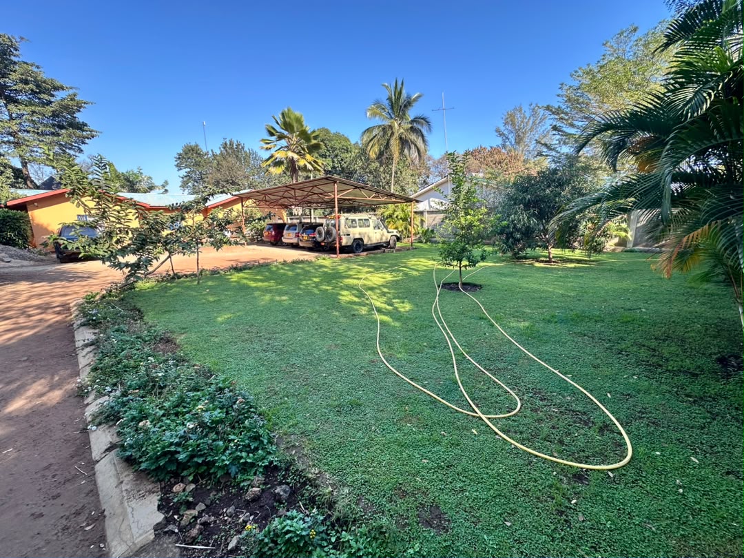 Garden beds and a green lawn leading toward covered vehicle parking.